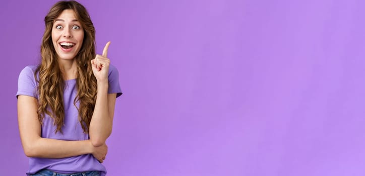 Excited cheerful happy creative smart girl raise index finger eureka gesture smiling broadly stare camera thrilled got excellent idea share suggestion think up perfect solution purple background. Lifestyle.