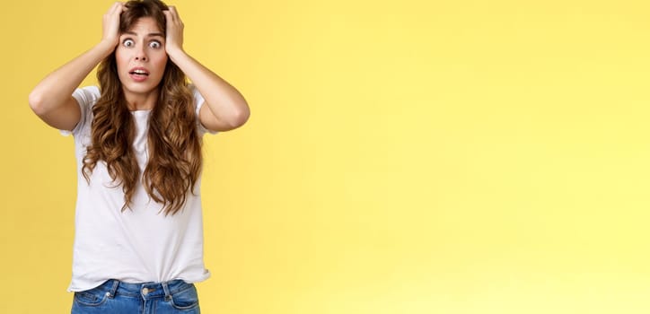 Troubled concerned anxious panicking woman female employee lose control grab head nervously stare camera frustrated scared gasping hopeless puzzled standing yellow background.