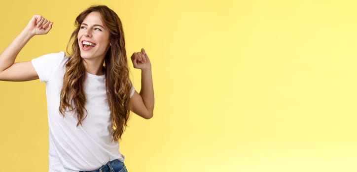 Yeah let perfect summer days behind. Daring good-looking happy charismatic young woman curly haircut gaze left pleased carefree having fun raise hands up celebratory victory winning success.