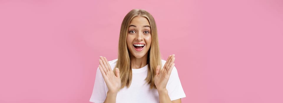 Woman learning awesome great news clasping hands in joy and excitement rejoicing feeling hapyp for friend smiling broadly and looking cheerful at camera with amused expression over pink background. Body language and emotions concept
