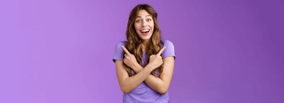 Lively surprised charismatic curly girl fascinated look admiration joy picking between awesome opportunities amazed excellent choices pointing sideways left right make decision purple background.