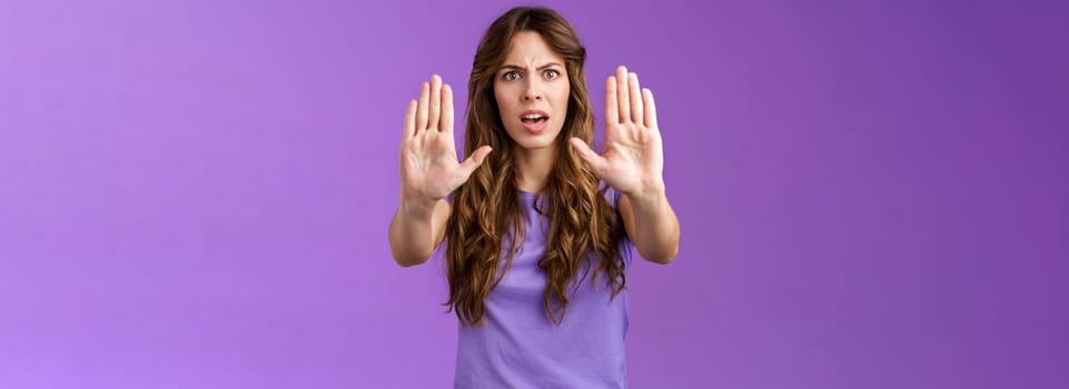 You need stop hold it. Serious-looking intense displeased woman pull hands prohibition taboo sign frowning demand enough shooting me bad mood restict doing mistake purple background.