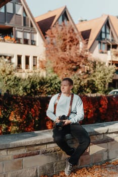 Man Sitting on Stairs in Old European City And Holding Photo Camera. Contemporary Stylish Blogger And Photographer