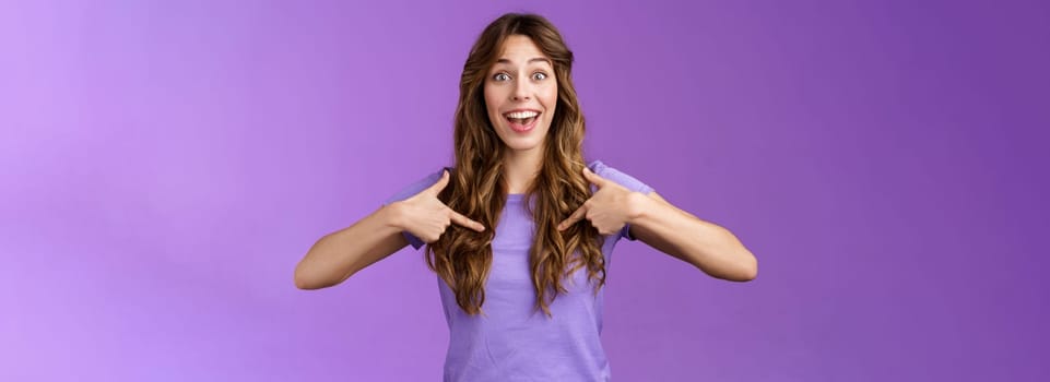 Cheerful lively upbeat entertained happy girl curly hairstyle open mouth amused pointing center herself happily tell own achievement smiling broadly telling friends promotion purple background.