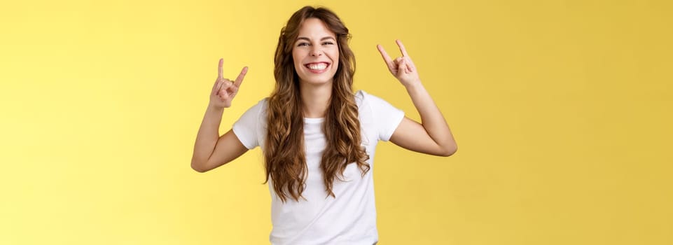 Enthusiastic charismatic lucky girl having fun enjoy awesome music show rock-n-roll gesture grinning thrilled like heavy-metal dancing upbeat positive standing entertained yellow background. Lifestyle.