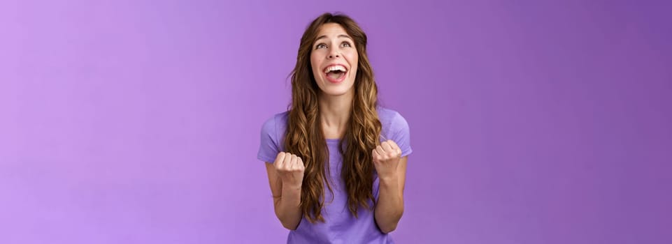 Relieved happy girl thank god awesome achievement celebrate success implore lord grateful fist pump yelling raise head up sky triumphing good news stand purple background joyful positive reaction. Lifestyle.