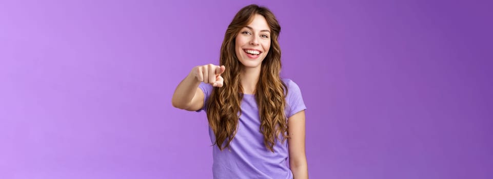 Entertained amused attractive lively girl curly hairstyle laughing happily pointing you finger indicate camera make choice smiling broadly assured believe decision right stand purple background.