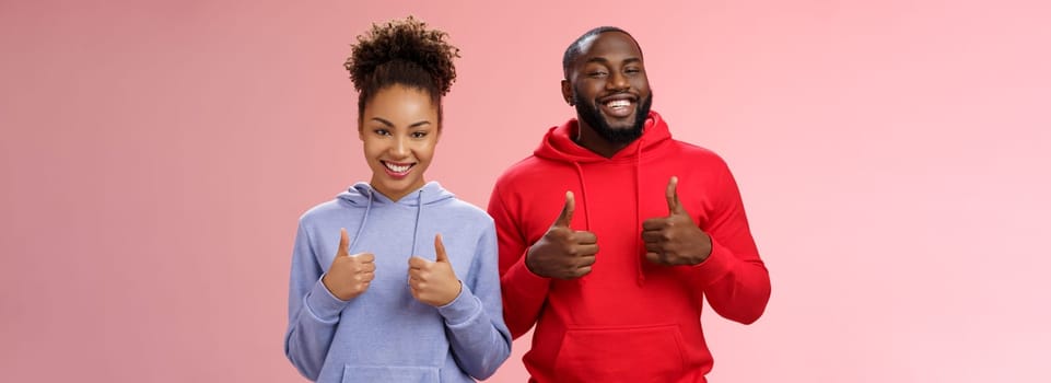 Best friends support your choice. Portrait proud satisfied good-looking african-american man woman show camera thumbs-up smiling broadly cheering liking awesome purchase, standing pink background.