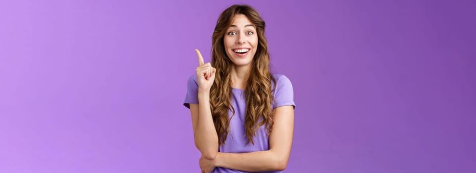 Got excellent idea. Attractive cheerful curly-haired female raise index finger eureka gesture smiling broadly made decision think up good plan share thought grinning ambushed purple background.