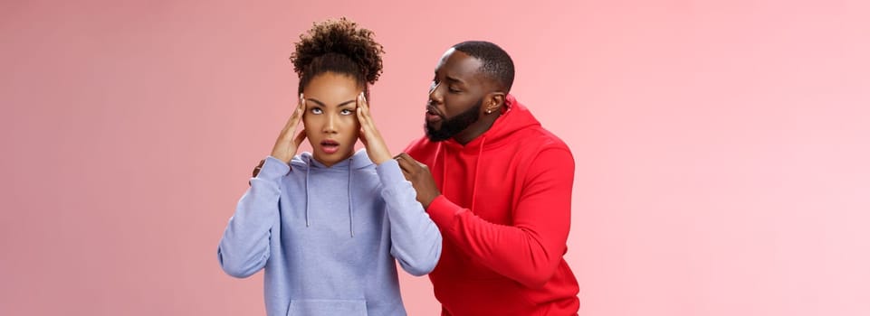 Man apologizing girlfriend behind back touching shoulder comforting girl feel pressured irritated fed up lying hear boyfriend sorry arguing standing bothered pink background, couple fighting.