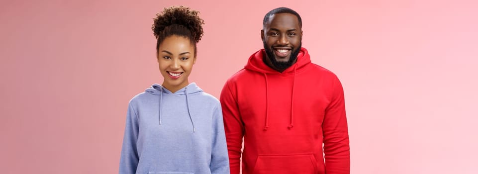 Friendly two african american man woman standing together smiling broadly coworkers present collective project receive good feedback grinning delighted like working pair, standing pink background.