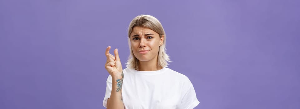 Woman feeling regret lacking small amount of money to afford car. Unhappy displeased good-looking stylish female with tattoos on hands frowning and pursing lips shaping tiny or little object.