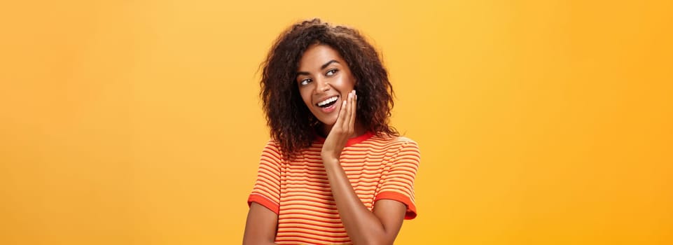 Cute creative and feminine stylish african american young female in striped t-shirt leaning head on palm gazing left with curious and adorable expression delightfully listening interesting story. Lifestyle.