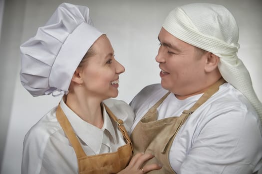 Cute oriental family with wife and husband cooking in kitchen on Ramadan, Kurban-Bairam, Eid al-Adha. Funny couple of cooks at joke photo shoot. Pancakes, pastries, Maslenitsa, Easter