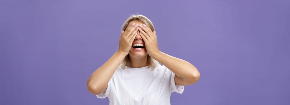 Can I look now. Portrait of excited pleased attractive tanned girlfriend in white t-shirt closing eyes and smiling broadly waiting for boyfriend bring surprising gift over purple background.