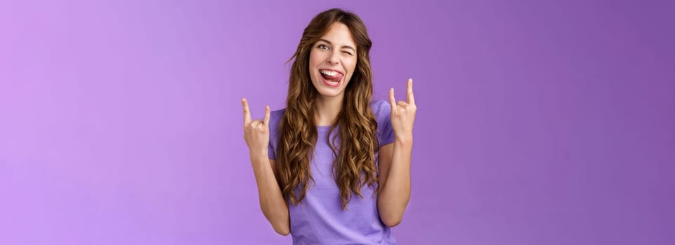 Daring sassy funny attractive woman having fun enjoy awesome party arrange music concert gathering show rock-n-roll heavy metal sign joyful stick tongue wink cheeky purple background. Lifestyle.