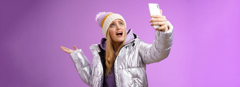 Upset bothered whining blond girl complaining cannot find right angle take selfie with cool sightseeing during vacation travelling abroad yelling smartphone pointing aside, purple background.