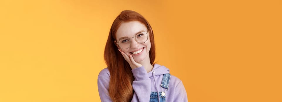 Smiling satisfied happy redhead girl get rid acne delighted touching soft clean skin laughing joyfully talking feel confidence self-assured own beauty, standing orange background enjoy communication.