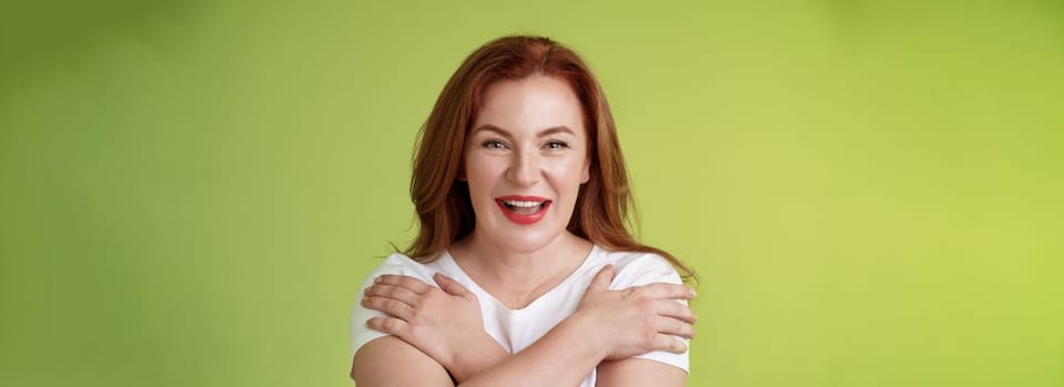 Cheerful charismatic happy good-looking redhead woman red lipstick cross hands chest smiling motivated excited having fun playful thrilled mood grinning enthusiastic standing green background.