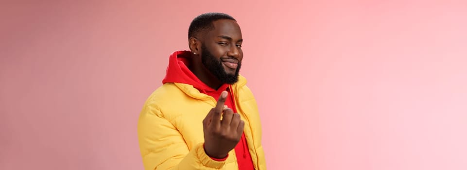 Cheeky flirty black bearded guy asking come closer beckon index finger camera smiling make smug face have plans for you alluring join, standing pink background devious grin. Emotions concept