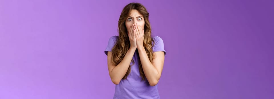 Shocked concerned ambushed scared intense girl gasping hold scream cover mouth stare camera frightened speechless learn terrible bad news stand purple background distressed upset.