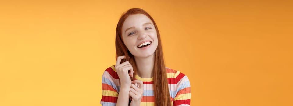 Silly good-looking flirty lively redhead young girl laughing playing coquettish ginger hair strand chuckling amused funny boyfriend jokes having fun awesome romantic date, orange background.