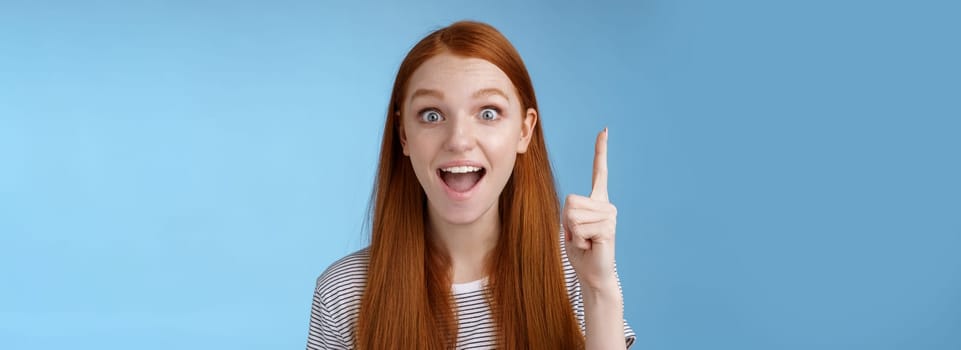 Excited good-looking cheerful ginger girlfriend add idea conversation raise index finger eureka gesture open mouth wide tell suggestion smiling broadly pondering excellent variant, blue background.