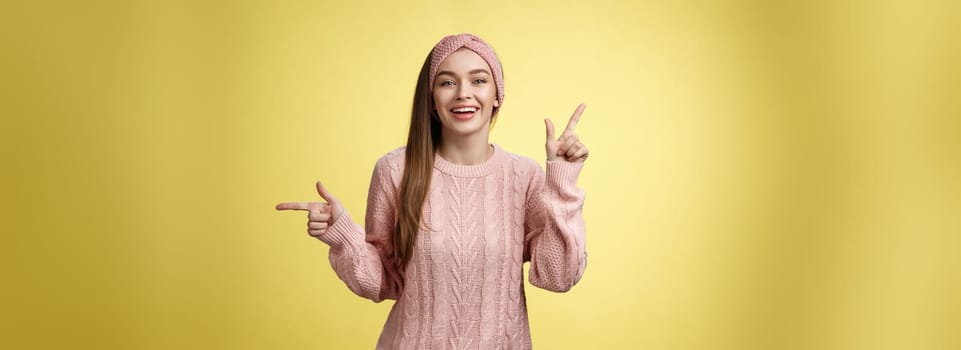 Pick what want. Charismatic cheerful young female student in headband, sweater pointing up, indicating right smiling cute, promoting advertisement showing opportunities and choices over white wall.