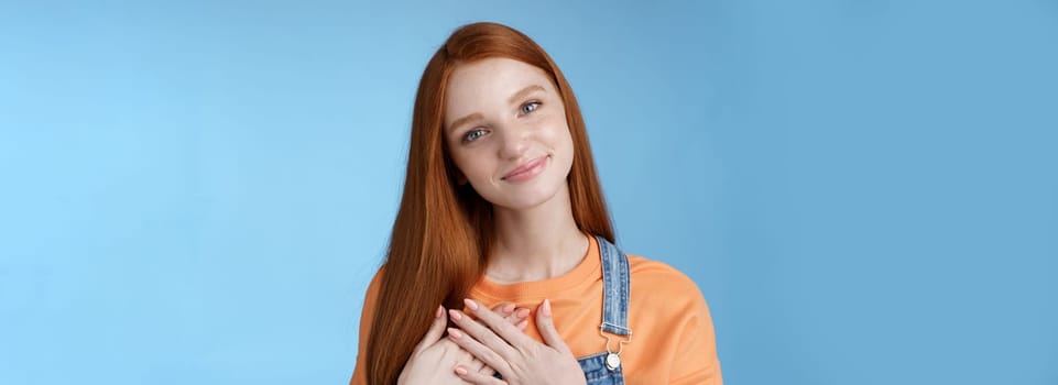Touched romantic tender cute redhead feminine girl blue eyes tilting head melting heartwarming gesture receive gladly pleasant prest touch heart smiling grateful, feel romance love, blue background.