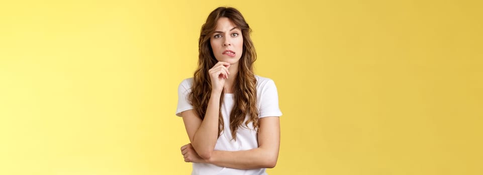 Troublesome situation give sec think. Intrigued thoughtful focused smart girlfriend thinking touch chin bite lip look camera focused pondering choice making decision solve problem yellow background.