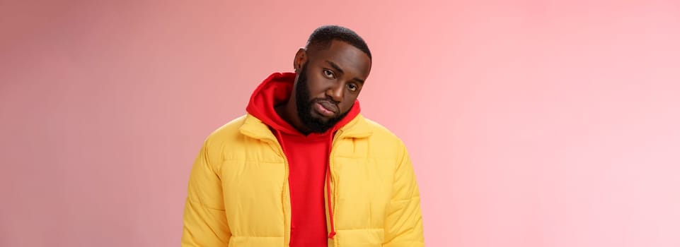 Unimpressed bored ignorant young african bearded man tilt head look scorn uninterest camera listen boring useless information, standing careless in yellow jacket red hoodie, indifferent.