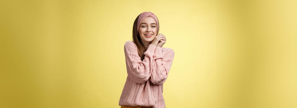 Cheerful glamour young pretty european female in pink cozy knitted headband, sweater leaning on hands pressing palms together silly seeing cute animal, feeling delight compassion, tender emotions.