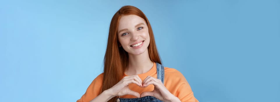 Love you. Attractive romantic tender redhead smiling gentle girlfriend blue eyes freckles show heart chest express sympathy romantic positive attitude confess passionate deep feelings, grinning cute.