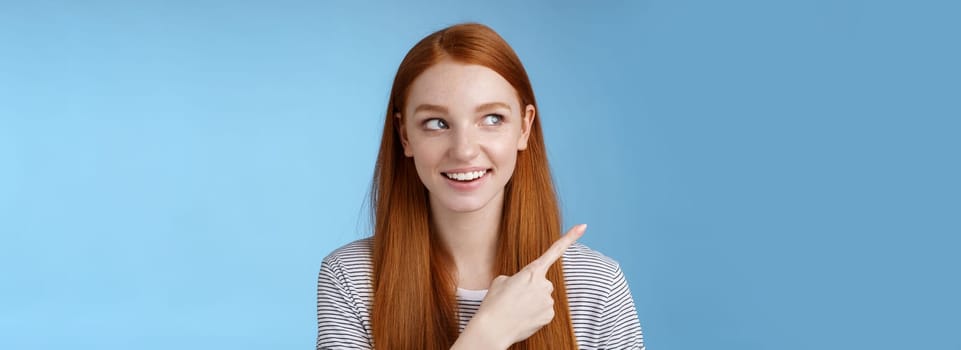 Intrigued good-looking redhead joyful curious girl watching looking upper left corner interested smiling broadly visit cool amusing place explore travelling new country astonished, blue background.