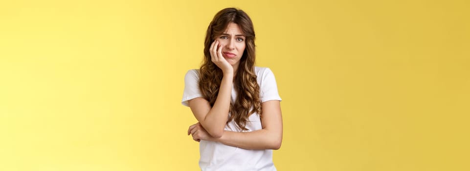 Upset distressed cute disappointed pretty girl feeling lonely regretting missed opportunity sighing sorrow sadness look camera apathetic indifferent lean face palm frowning jealous yellow background.