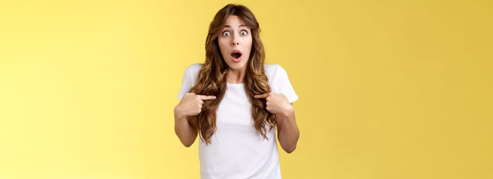 Shocked impressed speechless surprised girl gasping drop jaw pointing herself chest stare camera astonished unexpected promotion being chosen picked winning lottery stand yellow background.