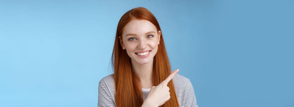 Close-up attractive gentle tender friendly-looking smiling redhead woman show place pointing upper left corner index finger grinning helpful giving choice help find store, standing blue background.