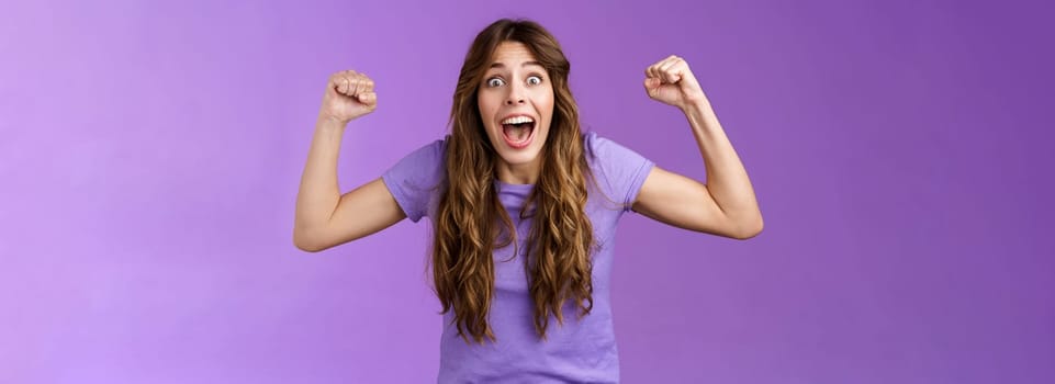 Excited happy cheerful curly-haired girlfriend cheering encourage team win rooting for friend raise hands fist pump celebration yelling enthusiastic, triumphing celebrate victory achievement.