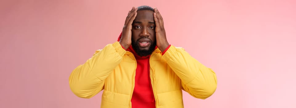 Shocked upset african-american bearded guy feel regret stunned hear terrible news hold hands head widen eyes stupor standing speechless troubled, look perplexed terribly sad, pink background.