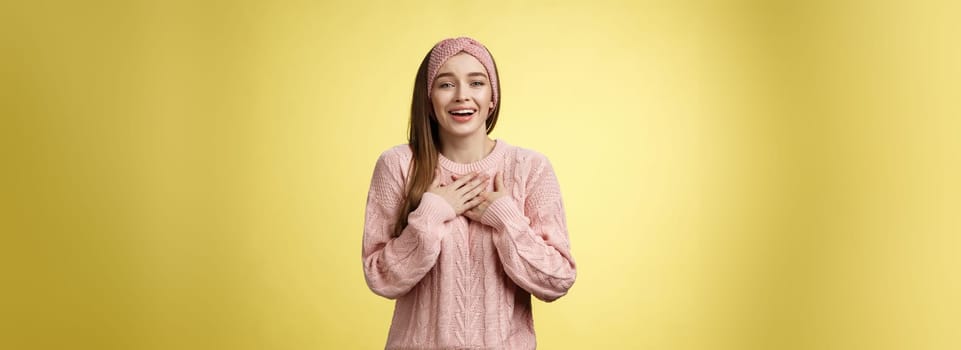 Grateful delighted charming young 20s woman wearing sweater pressing arms to chest happily, thankful, expressing gratitude, heartfelt appreciating gesture smiling amused, in love with romantic gift.