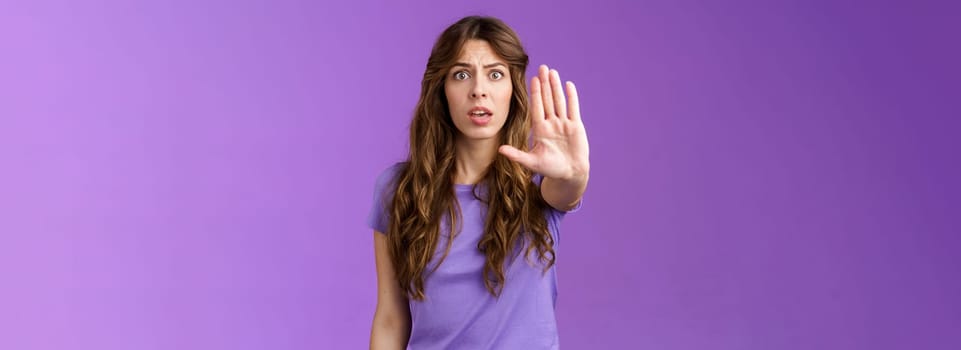 Worried shocked curly-haired woman gasping stare camera anxiously pull hand stop sign begging end prohibiting friend drive after drinking stand purple background forbid warn you purple background. Lifestyle.