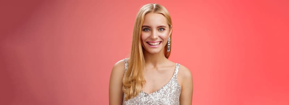 Charming glamour fabulous adult 25s blond woman in elegant silver dress shiny earrings smiling happily take part interesting conversation talking look friendly grinning, standing red background.