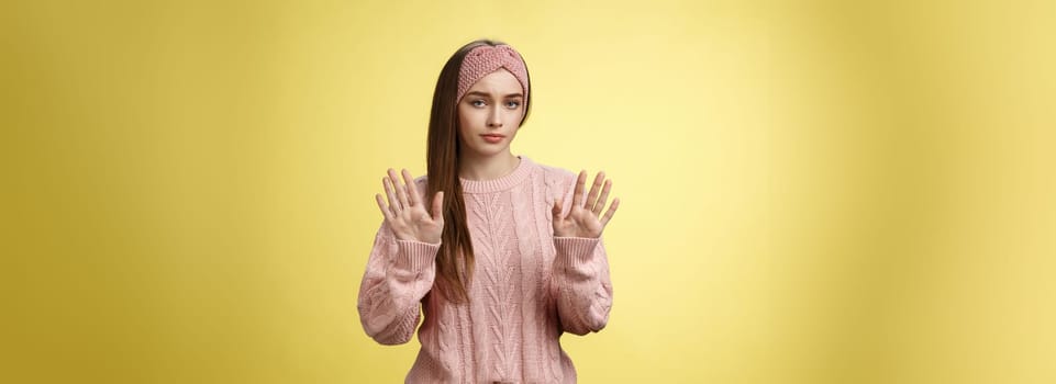 No thanks. Cute unamused picky young girl in knitted sweater, headband showing hold on, slow down, refusal gesture raising palms in rejection being reluctant unimpressed and indifferent to proposal.
