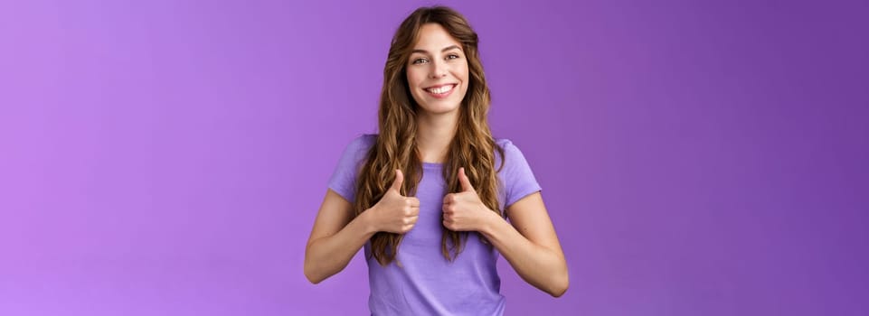 Upbeat positive attractive cheerful curly girl show thumbs up approval sign smiling delighted encourage friend good job well done standing satisfied like positive opinion purple background. Lifestyle.