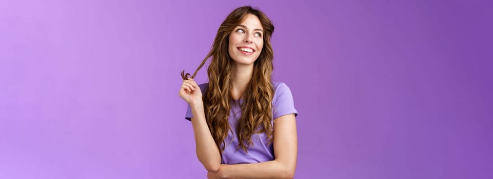 Lively arrogant good-looking girl curly stylish haircut look away dreamy delighted daydreaming thoughtful gaze away touch hair strand rolling curly smiling broadly stand purple background. Lifestyle.