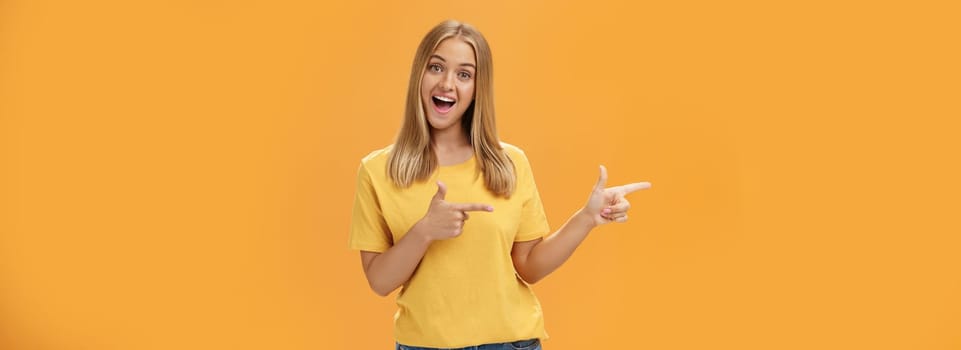 Check out copy sapce of dream. Upbeat good-looking pleasant female shop assistant in t-shirt pointing left with finger guns and smiling amused at camera recommending to watch that direction. Advertisement concept