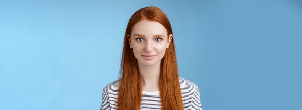 Excited good-looking confident young dreamy redhead girl blue eyes aimed success determined get job attend interview standing self-assured smiling friendly encourage herself, blue background.