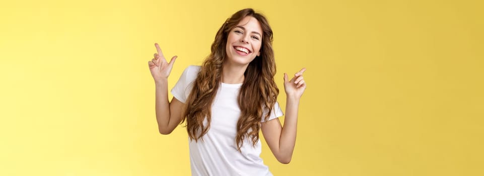 Outgoing cheerful attractive woman curly haircut wear casual white t-shirt dancing party having fun pointing up disco moves having fun smiling broadly enjoy holidays anticipating summer trip. Lifestyle.