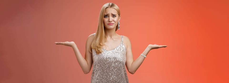 Nervous unsure doubtful cute blond woman struggle make decision shrugging pointing sideways frowning upset standing insecure feel pressure cannot decide choice make, frustrated red background.