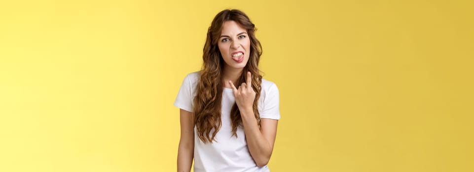 Yeah rocking this party. Rebellious daring cool good-looking sassy woman show tongue rock-n-roll gesture heavy metal having fun enjoy awesome concert express confidence yellow background.